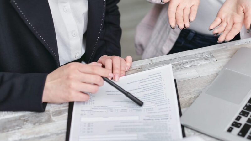 Headerbild: argvis; Kunden und Referenzen, die Hände von 2 Personen, die an einem Schreibtisch vor einem Laptop und einem Formular sitzen, sind zu sehen